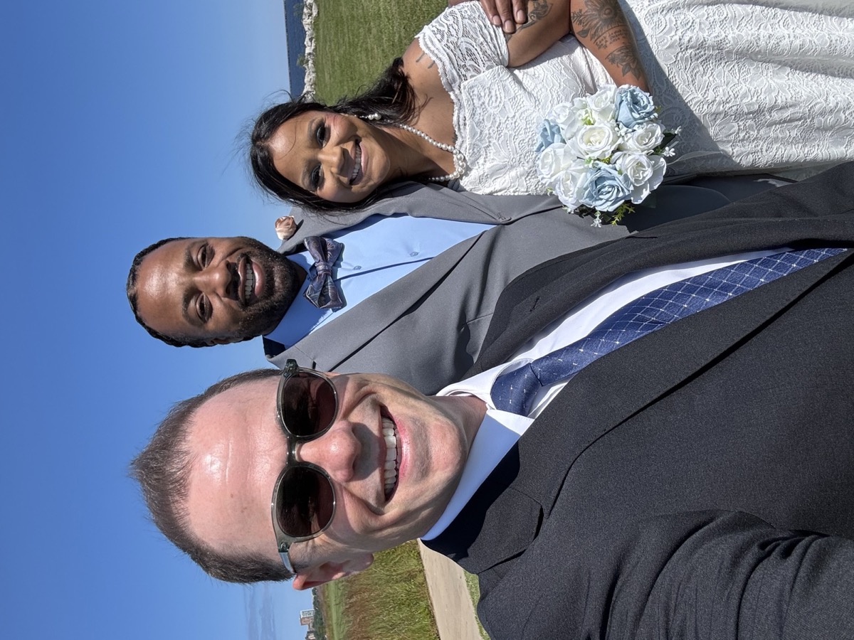 Wedding officiant Schwa Potter selfie with couple outdoors on sunny day