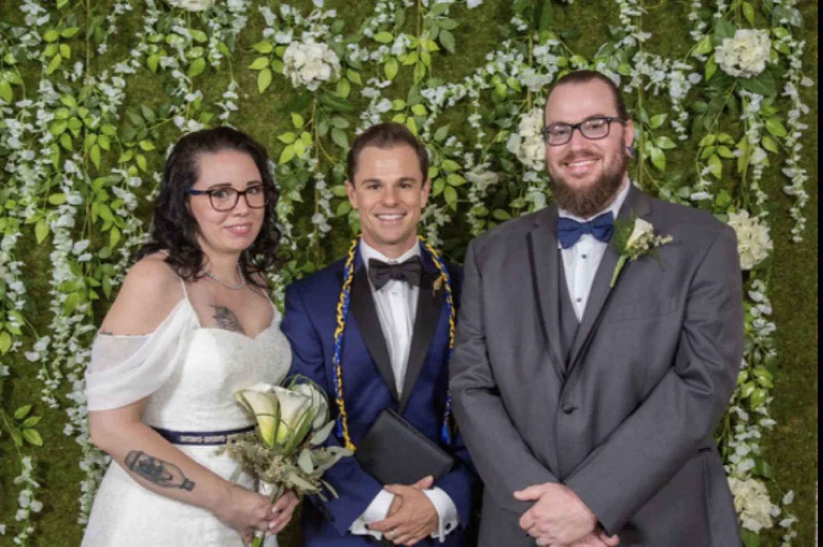 Couple with officiant Schwa Potter after handfasting ceremony with green wall backdrop